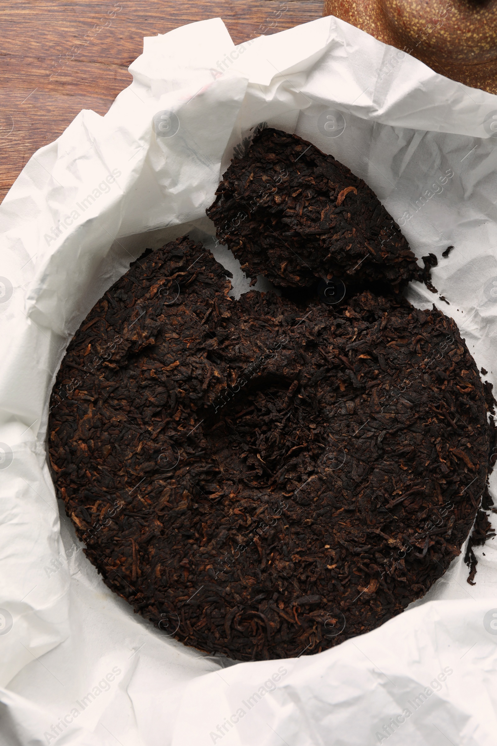 Photo of Broken disc shaped pu-erh tea on wooden table, top view