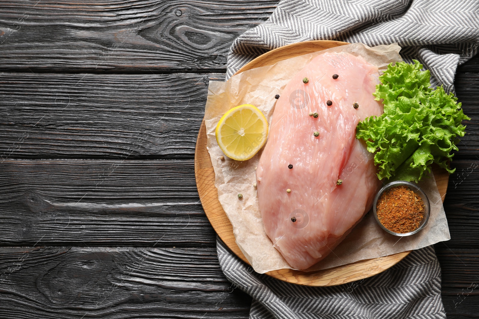 Photo of Plate with raw turkey fillet and ingredients on wooden background, top view. Space for text