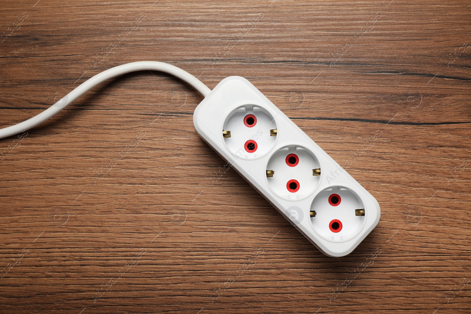 Photo of Extension cord on wooden floor, top view. Electrician's equipment