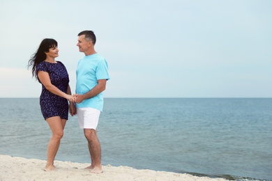 Happy mature couple spending time together on sea beach. Space for text