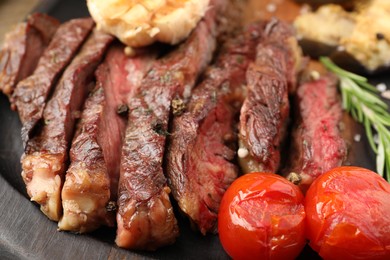 Photo of Delicious grilled beef with tomatoes and spices on tray, closeup