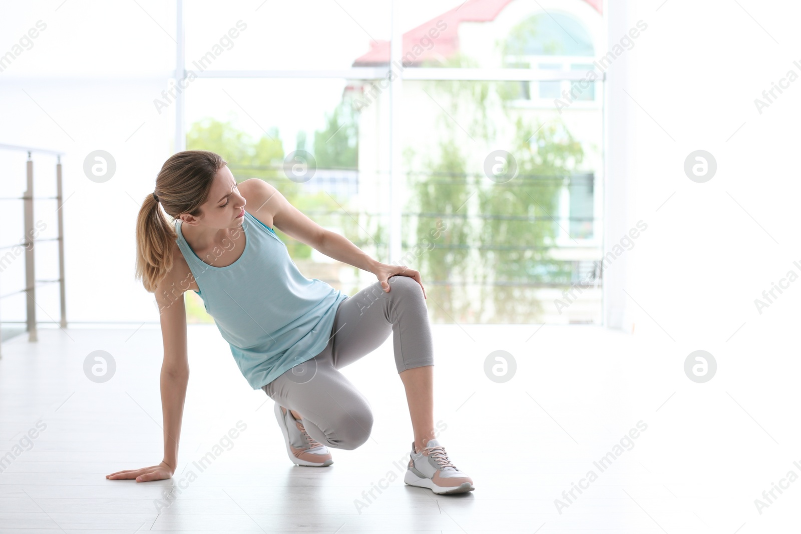 Photo of Woman in sportswear suffering from knee pain at gym