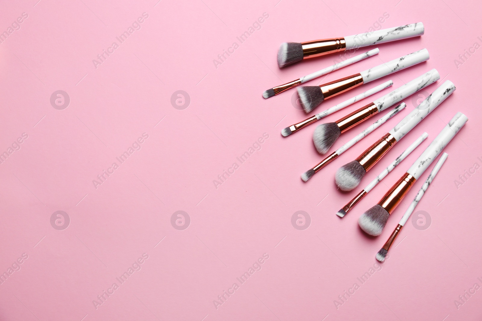 Photo of Different makeup brushes on pink background, flat lay. Space for text