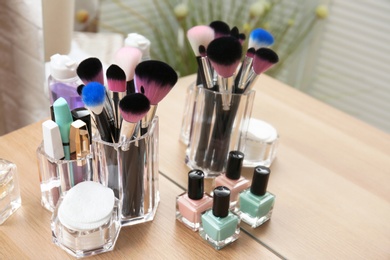 Organizer with makeup cosmetic products on wooden table near mirror