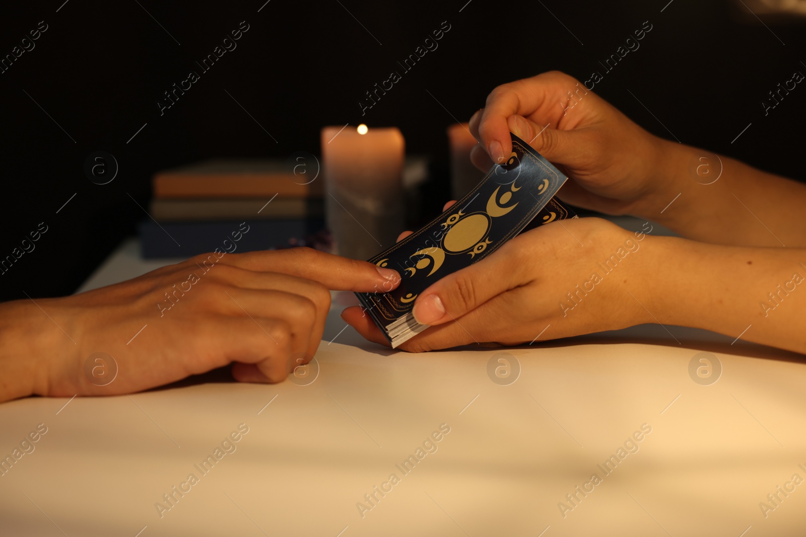 Photo of Astrologer predicting client's future with tarot cards at table, closeup