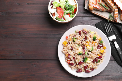 Photo of Delicious rice with beans served on wooden table, flat lay. Space for text