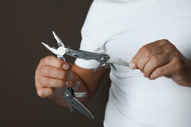 Man holding multitool on dark background, closeup