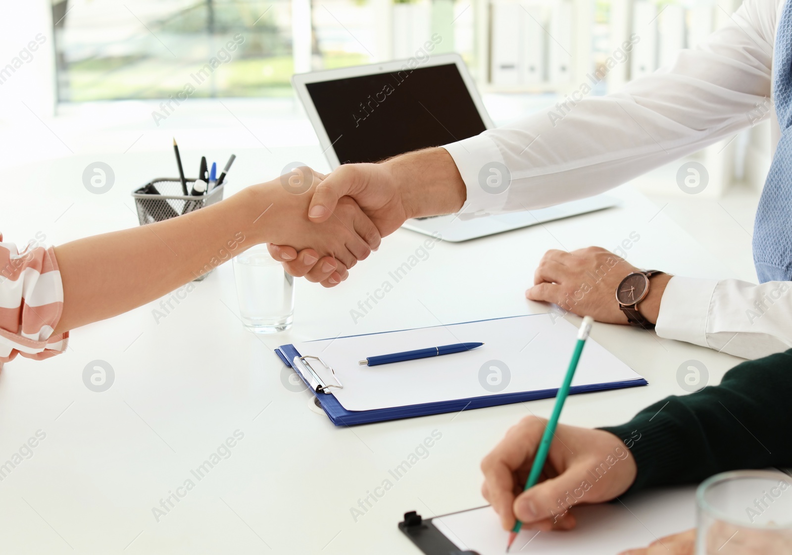 Photo of Human resources manager shaking hands with applicant during job interview in office