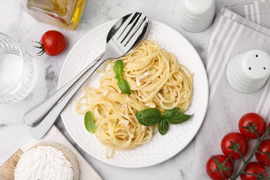 Delicious pasta with brie cheese and basil leaves served on marble table, flat lay