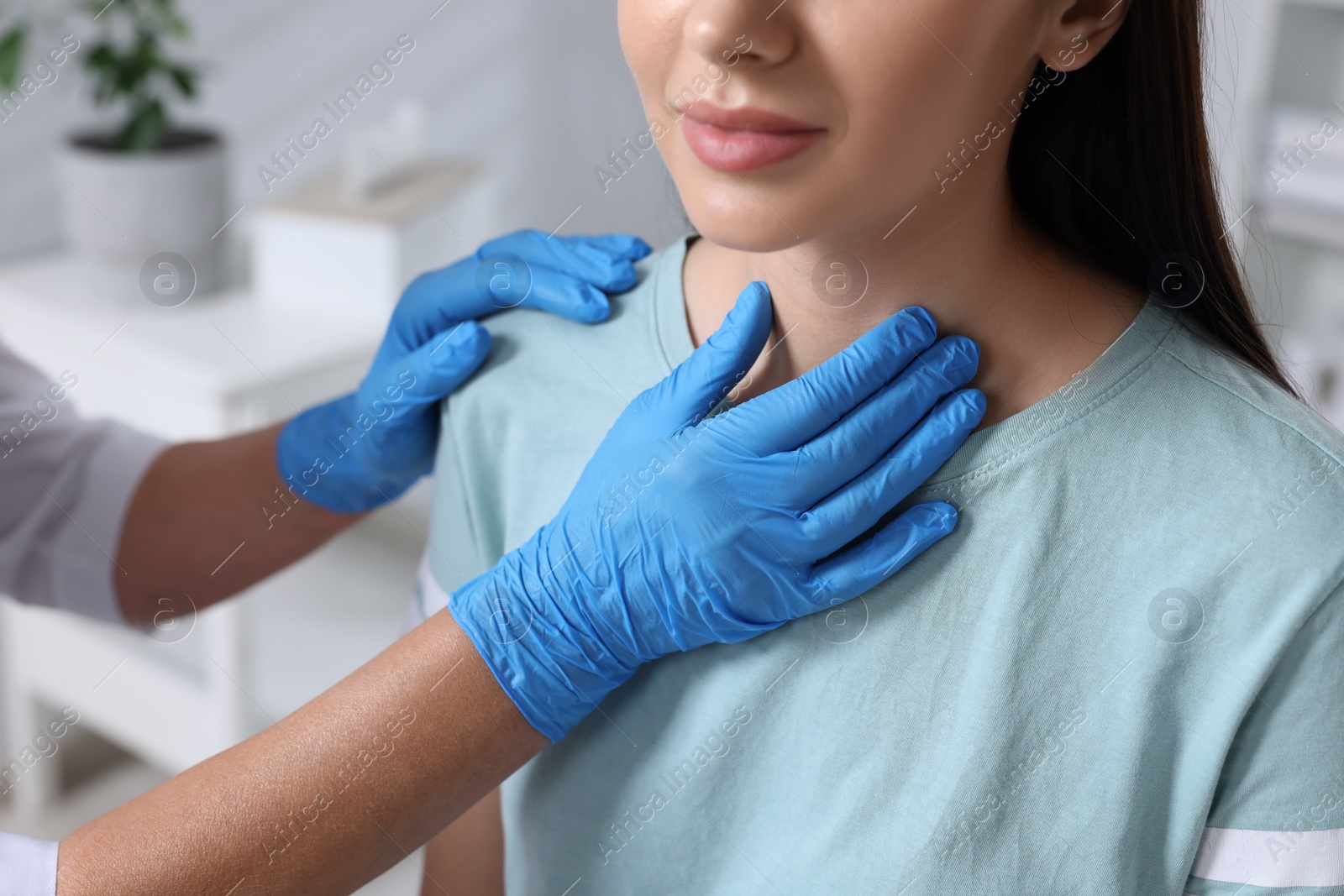 Photo of Endocrinologist examining thyroid gland of patient indoors, closeup