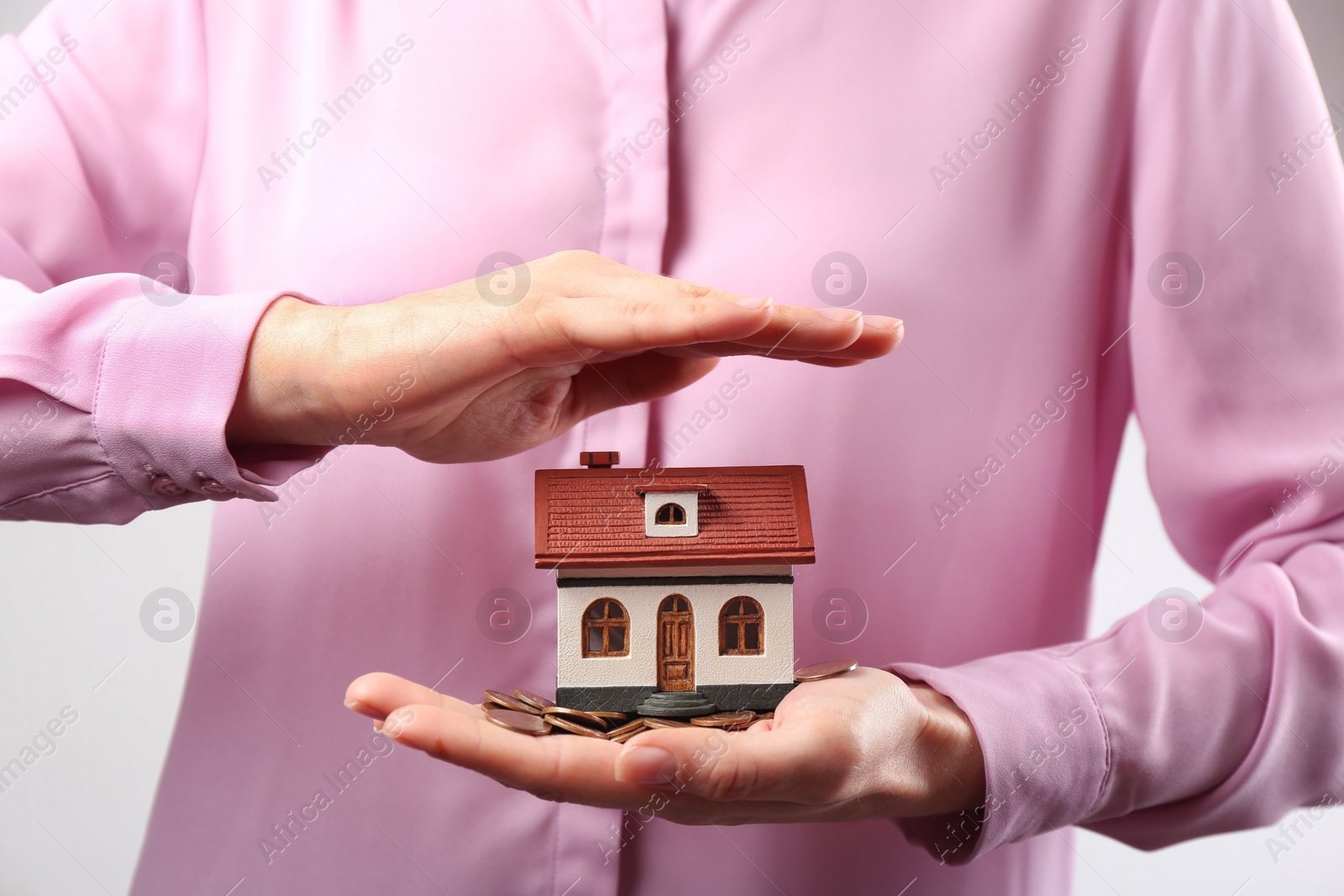 Photo of Woman holding house model and coins, closeup