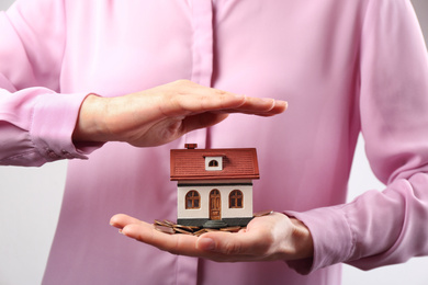 Woman holding house model and coins, closeup