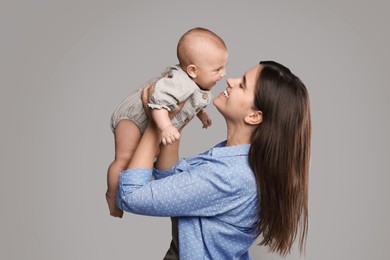 Photo of Beautiful mother with her cute baby on grey background