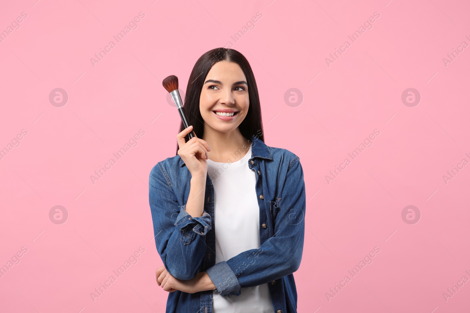 Photo of Beautiful woman with makeup brush on pink background