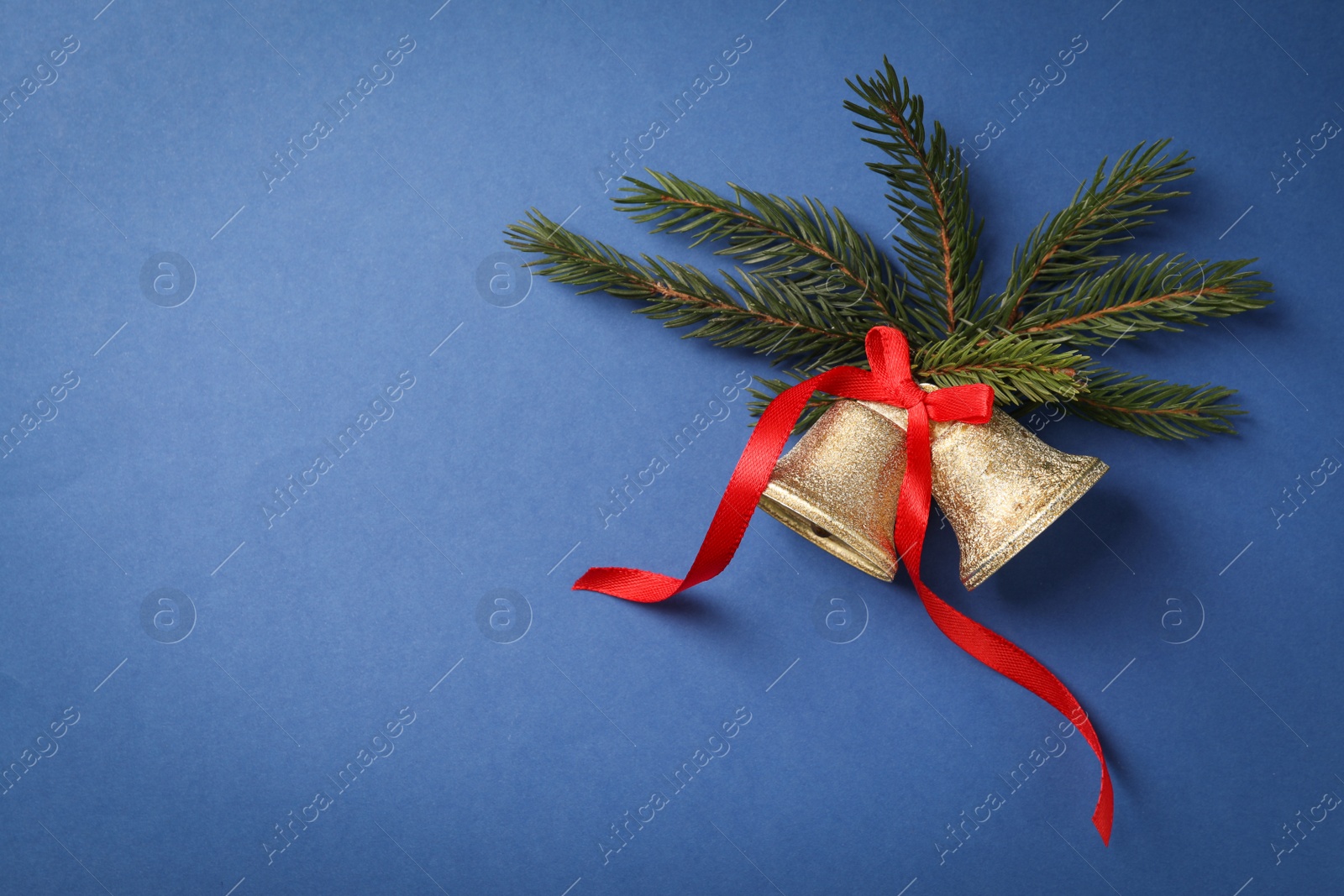 Photo of Bells and fir branches on blue background, flat lay with space for text. Christmas decor