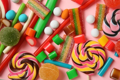 Many different yummy candies on color background, top view