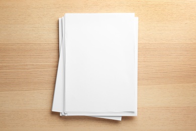 Photo of Stack of blank paper sheets for brochure on wooden background, top view. Mock up