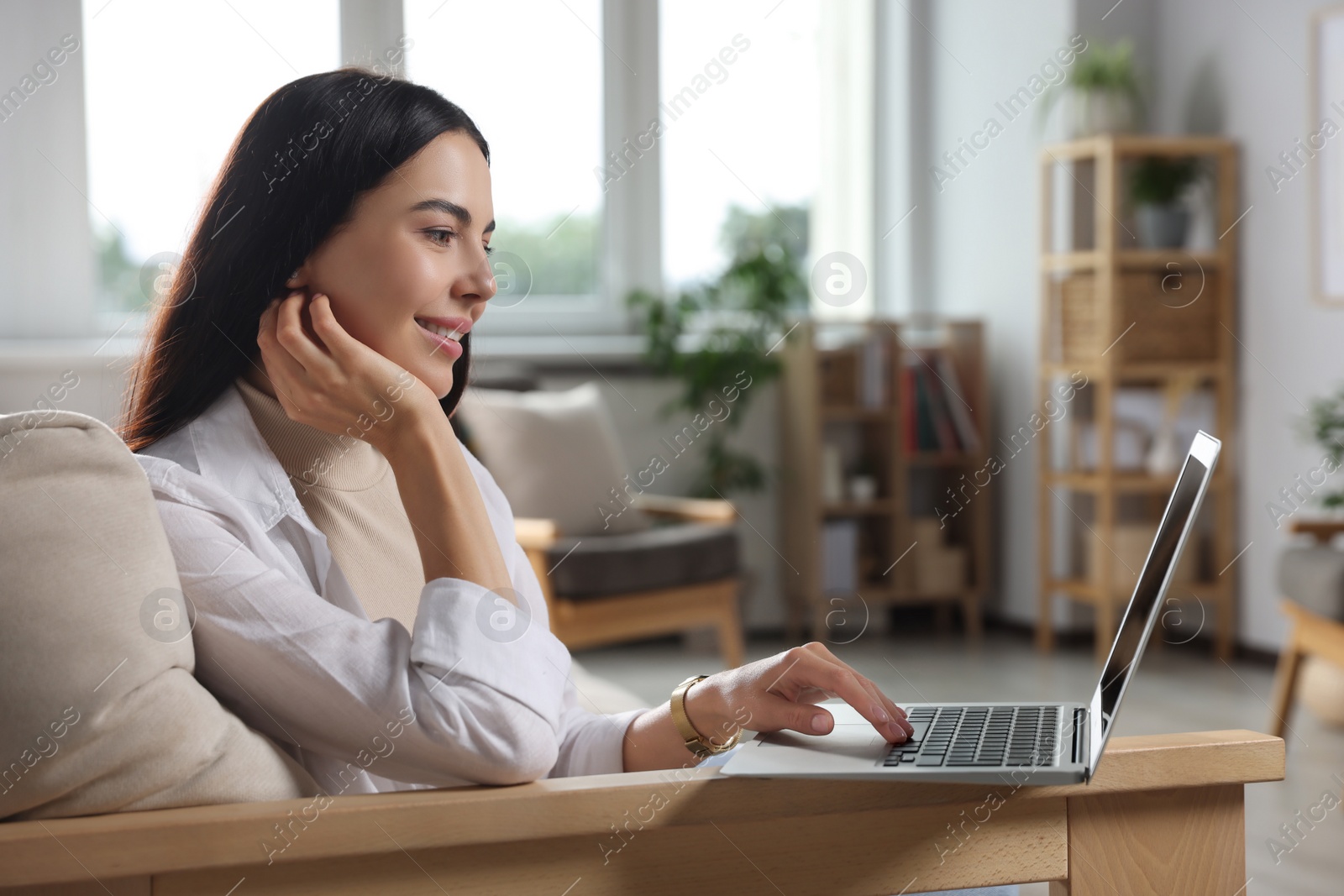 Photo of Young woman working with laptop on sofa at home