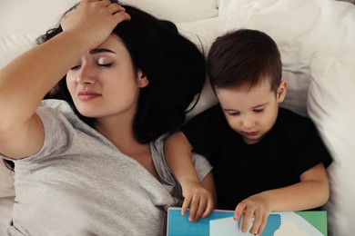 Photo of Depressed single mother with child in bed at home, above view