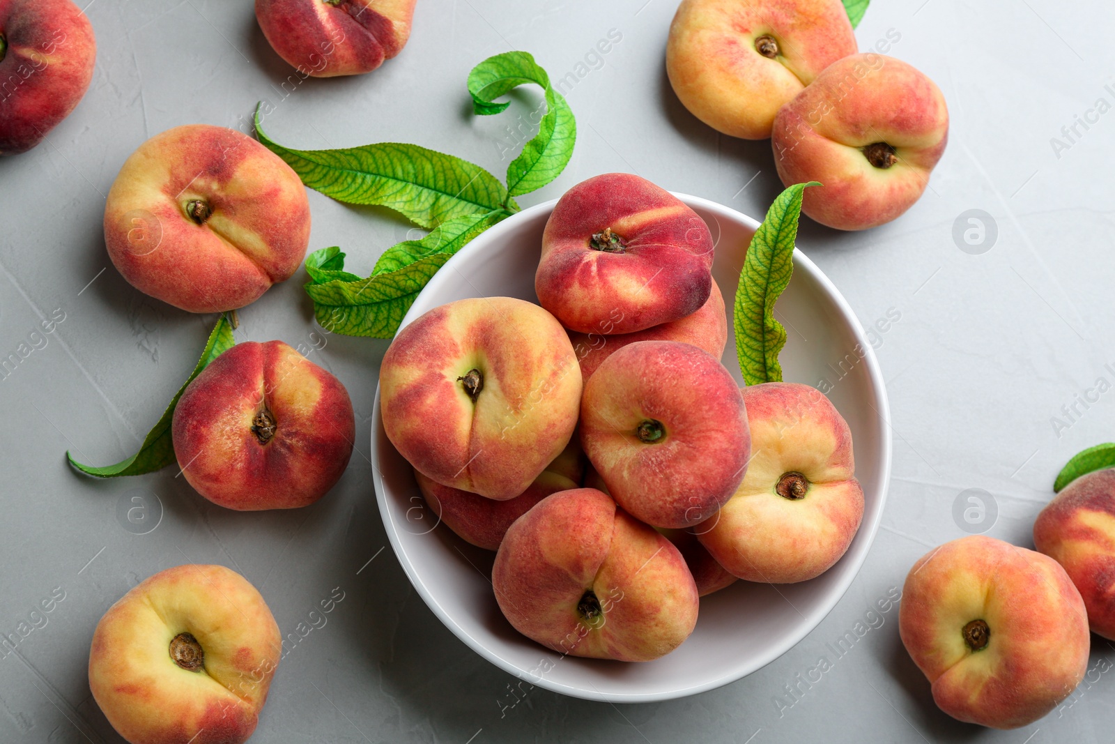 Photo of Fresh ripe donut peaches with leaves on light table, flat lay
