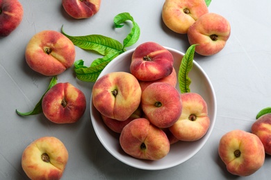 Fresh ripe donut peaches with leaves on light table, flat lay