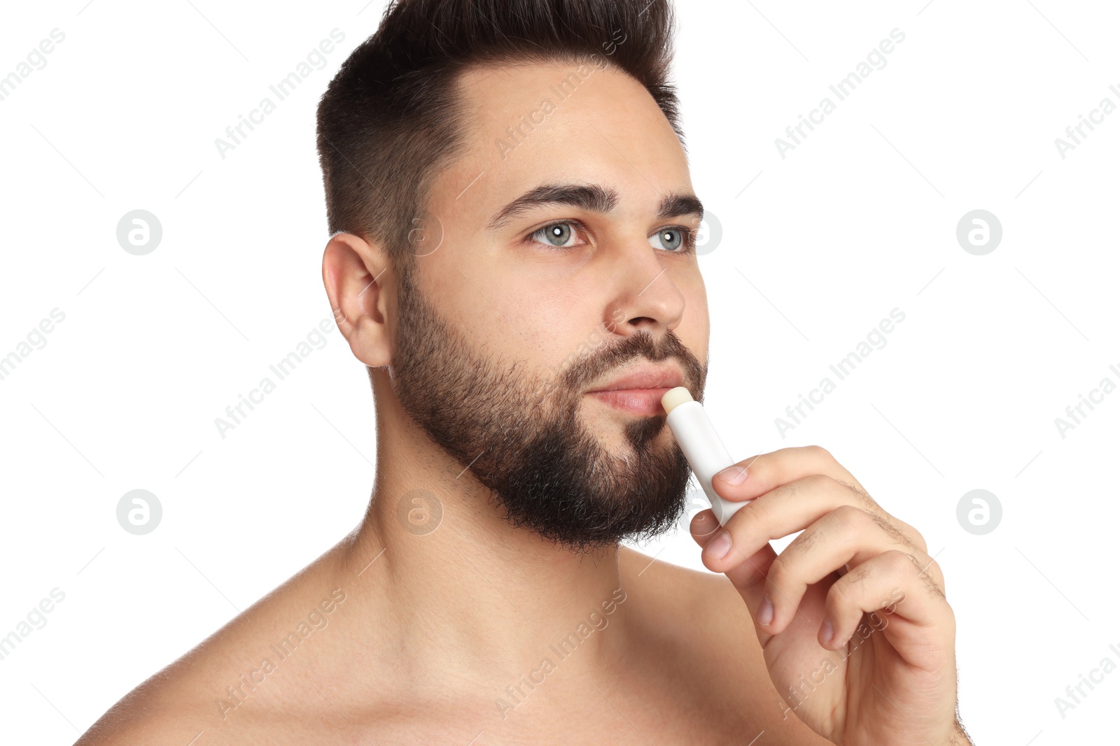 Photo of Young man applying lip balm on white background