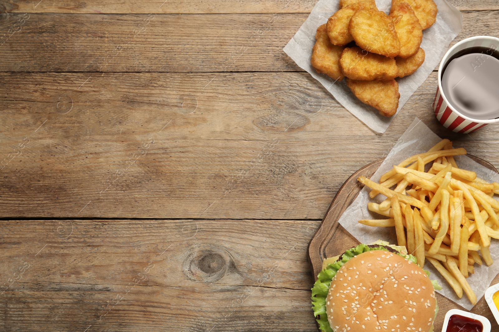 Photo of Flat lay composition with delicious fast food menu on wooden table. Space for text