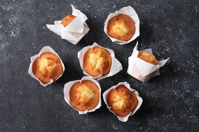 Delicious sweet muffins on black textured table, flat lay