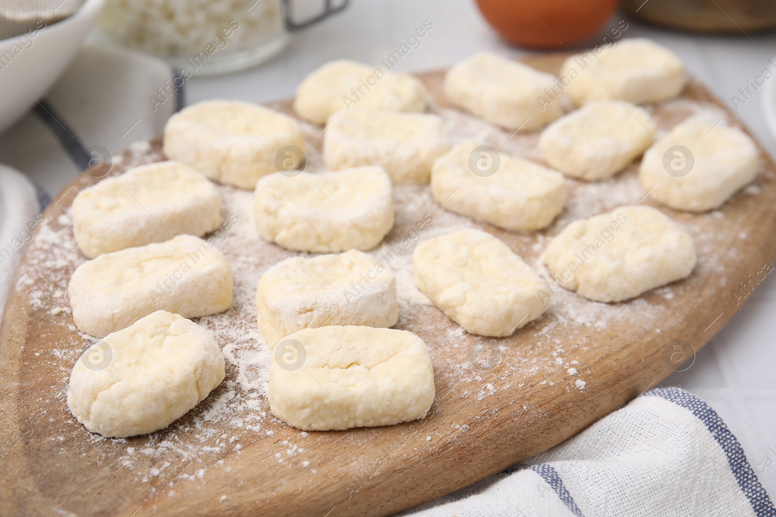 Photo of Making lazy dumplings. Wooden board with cut dough and flour on table, closeup