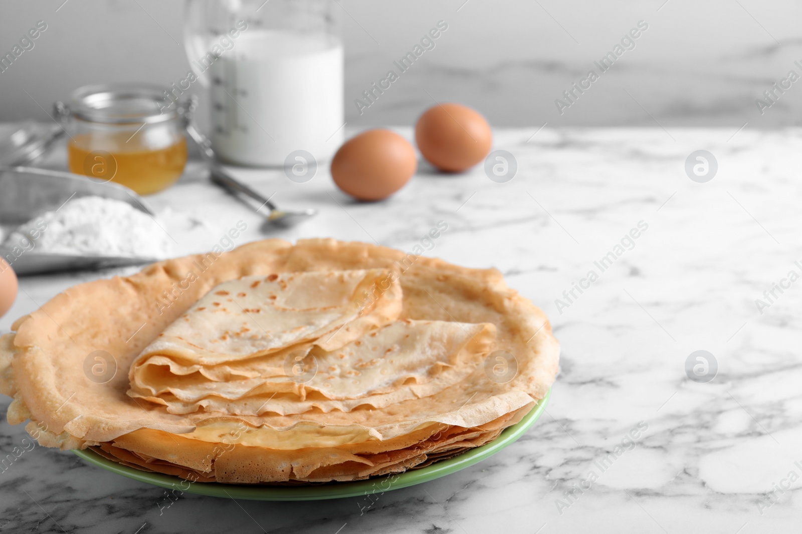 Photo of Delicious crepes on white marble table. Space for text