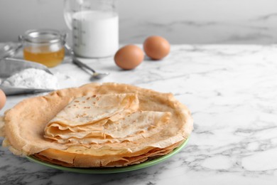 Photo of Delicious crepes on white marble table. Space for text