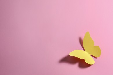 Photo of Yellow paper butterfly on pink background, top view. Space for text