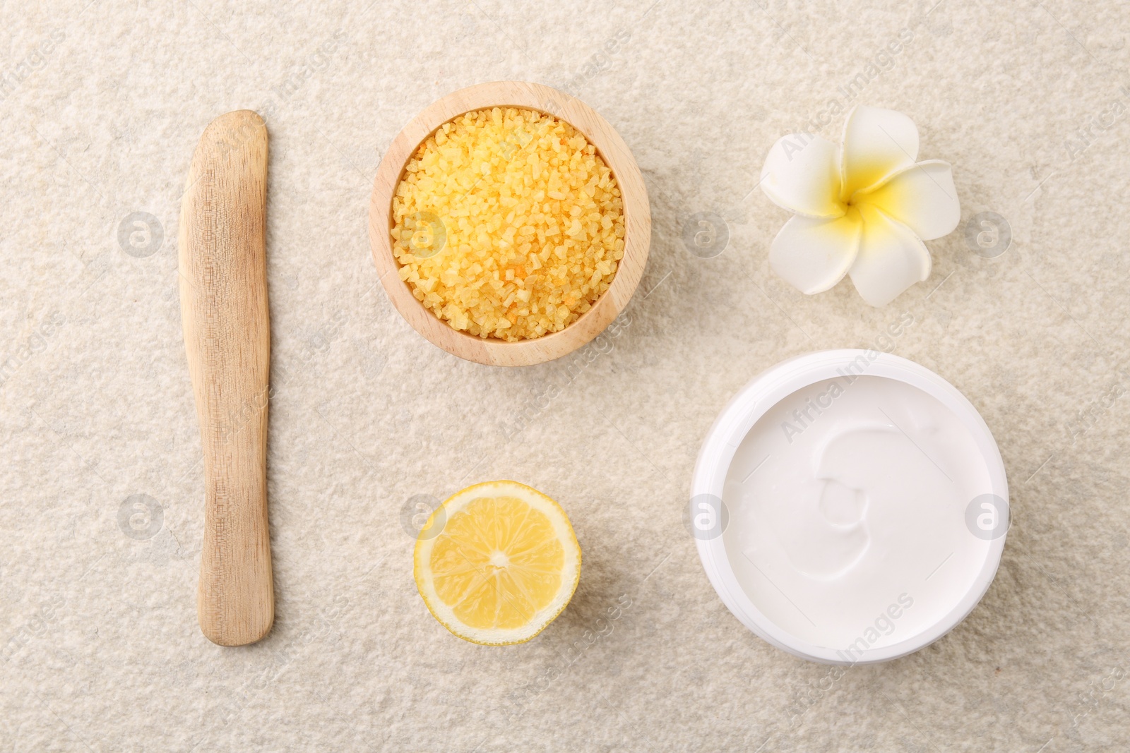 Photo of Flat lay composition with moisturizing cream in open jar and other body care products on light textured table