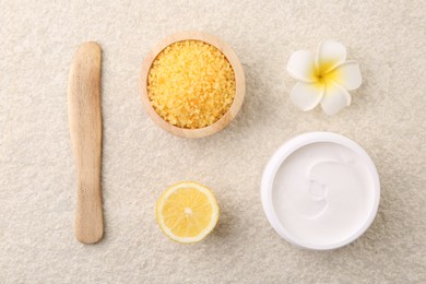 Flat lay composition with moisturizing cream in open jar and other body care products on light textured table