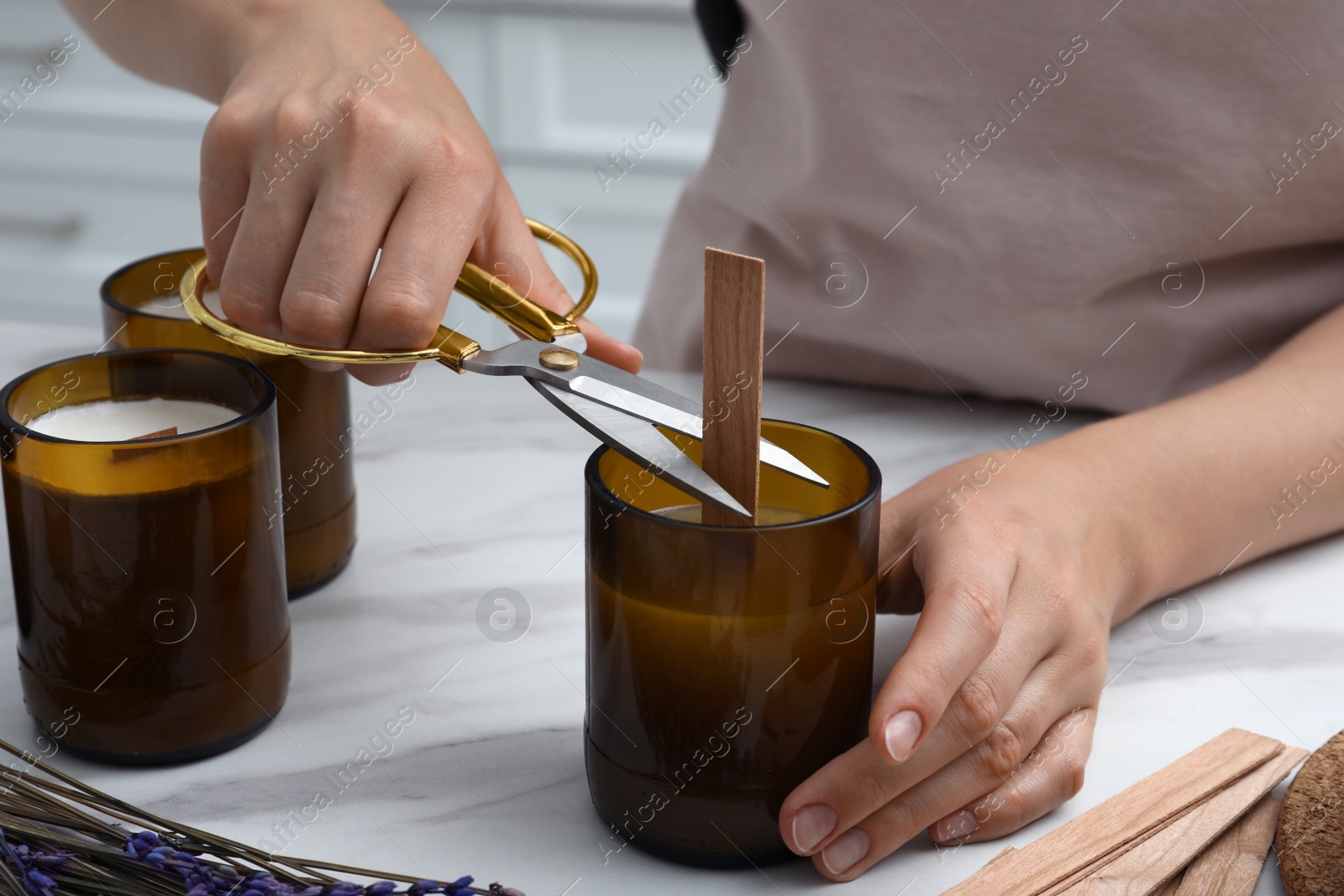 Photo of Woman cutting wick of homemade candle at table indoors, closeup