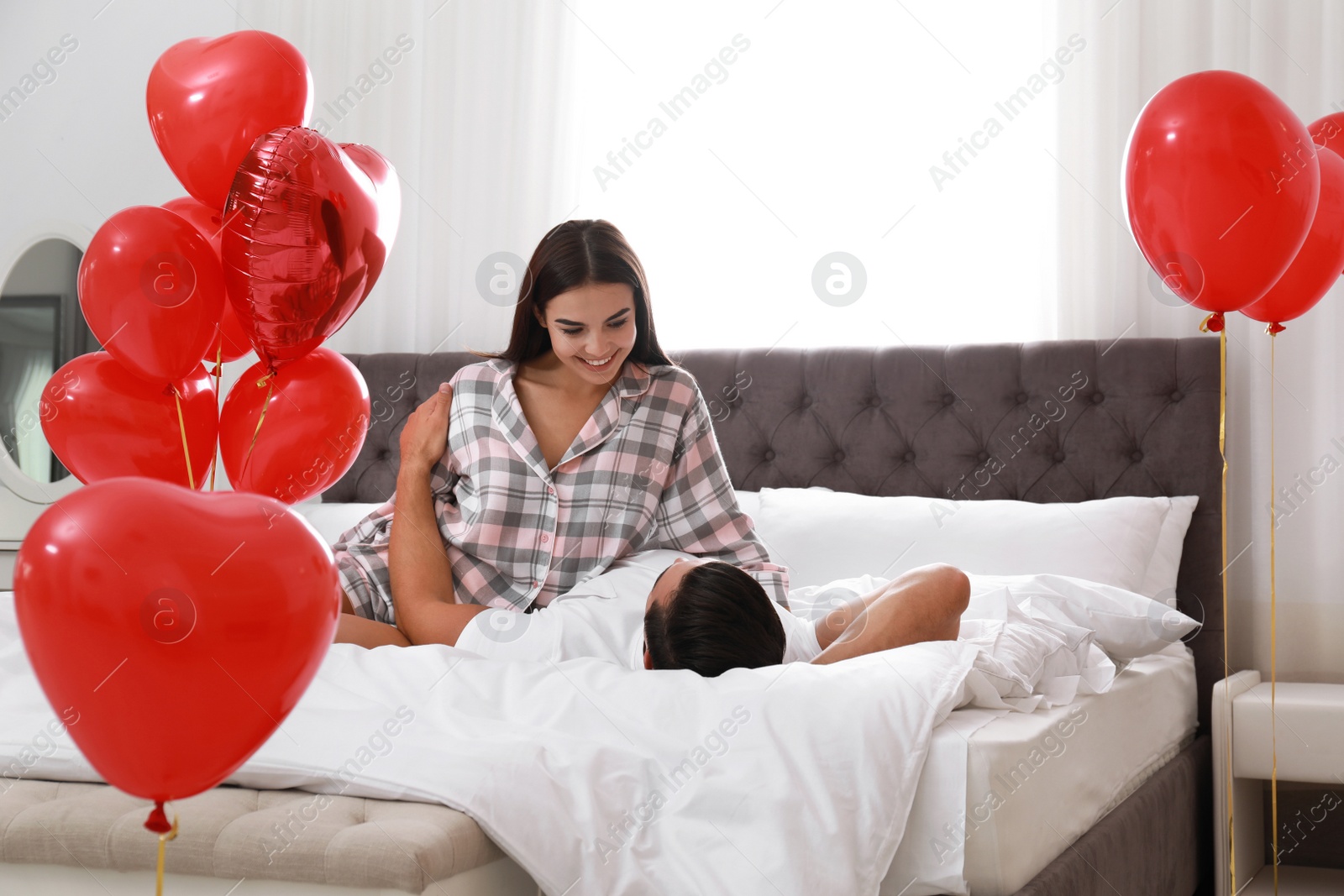 Photo of Beautiful couple with heart shaped balloons in bedroom