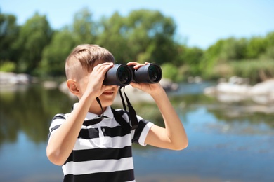 Photo of Little boy with binoculars outdoors. Summer camp