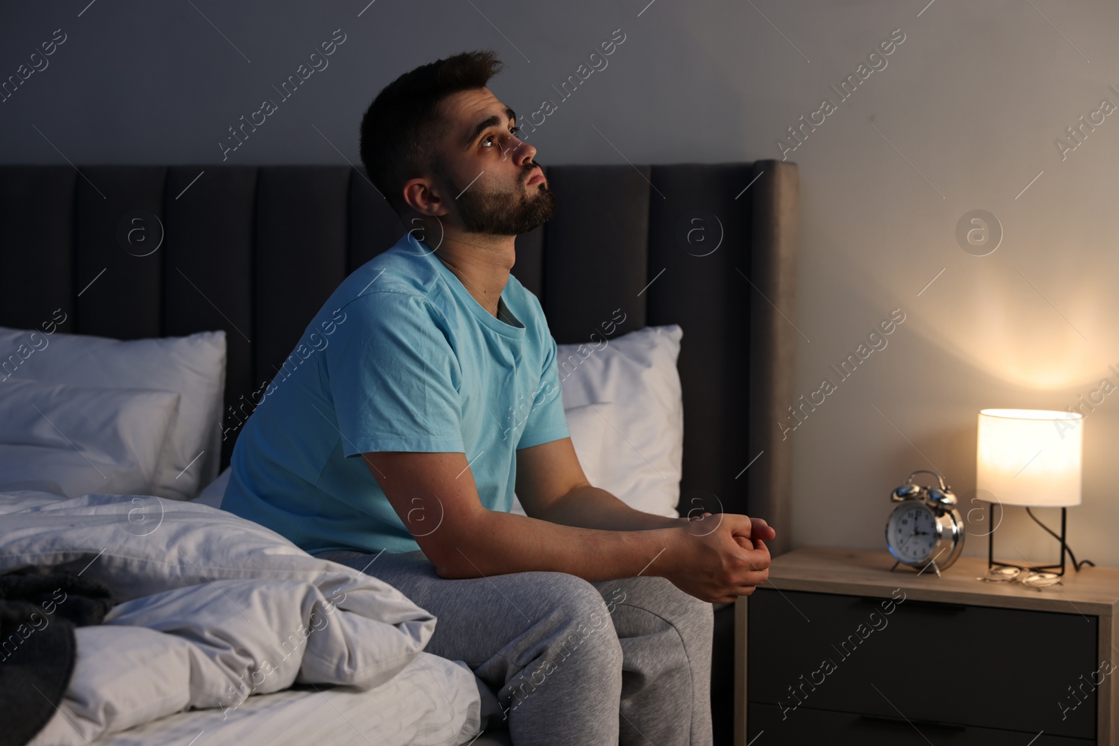 Photo of Man suffering from insomnia on bed at home