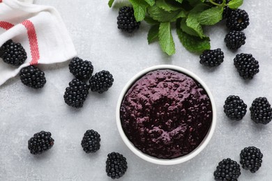 Photo of Blackberry puree in bowl and fresh berries on light grey table, flat lay