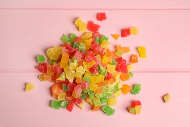 Photo of Mix of delicious candied fruits on pink wooden table, flat lay