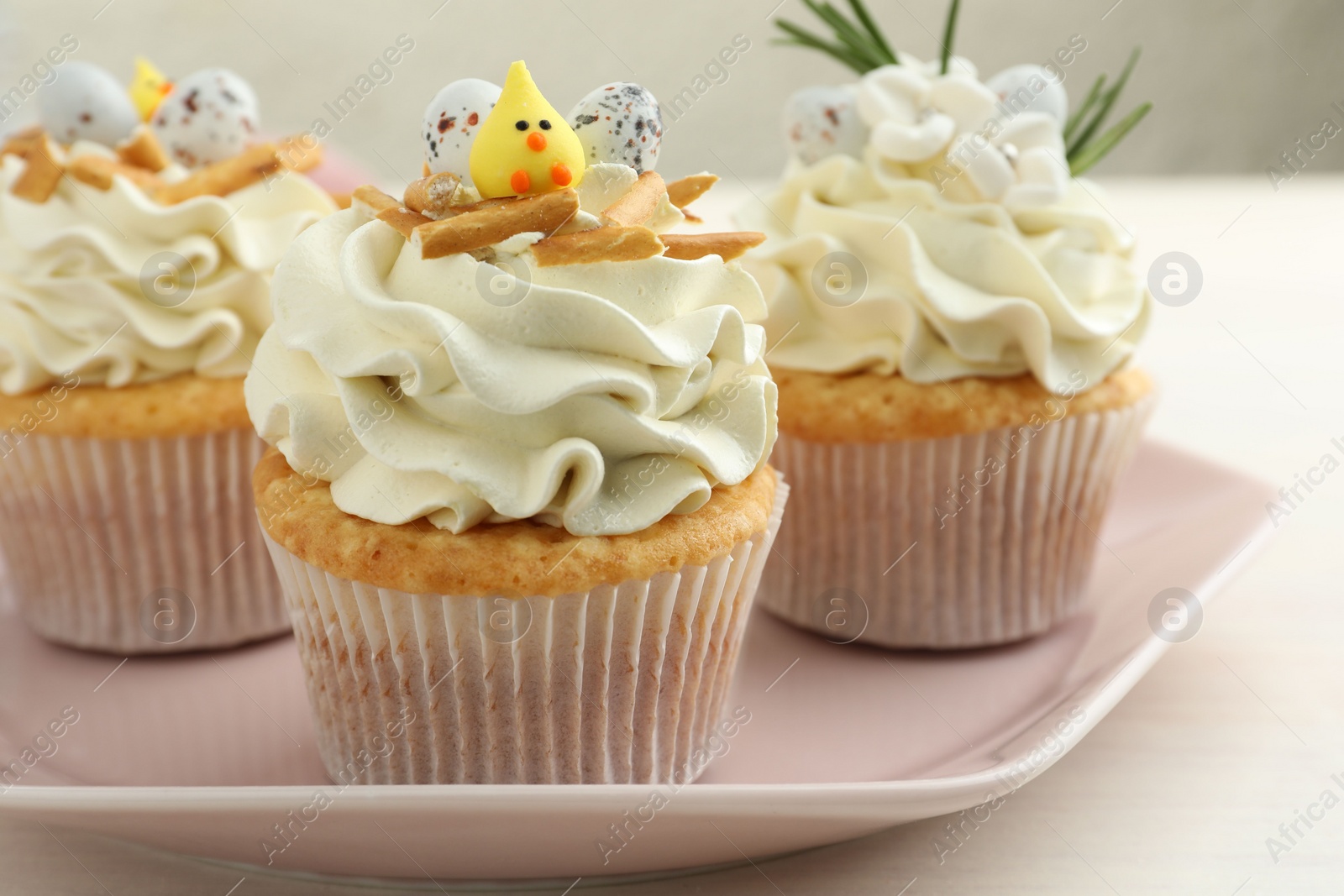 Photo of Tasty Easter cupcakes with vanilla cream on light table, closeup