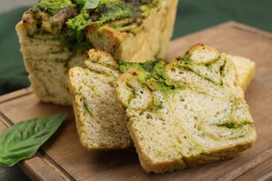 Photo of Freshly baked pesto bread on wooden board, closeup