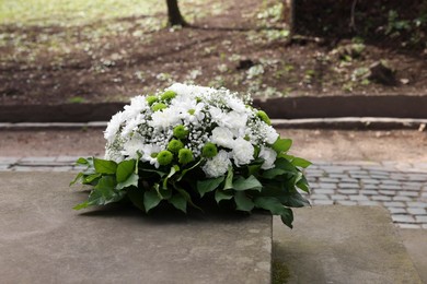 Photo of Funeral wreath of flowers on tombstone outdoors