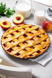 Photo of Delicious peach pie and fresh fruits on light kitchen table