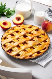 Delicious peach pie and fresh fruits on light kitchen table