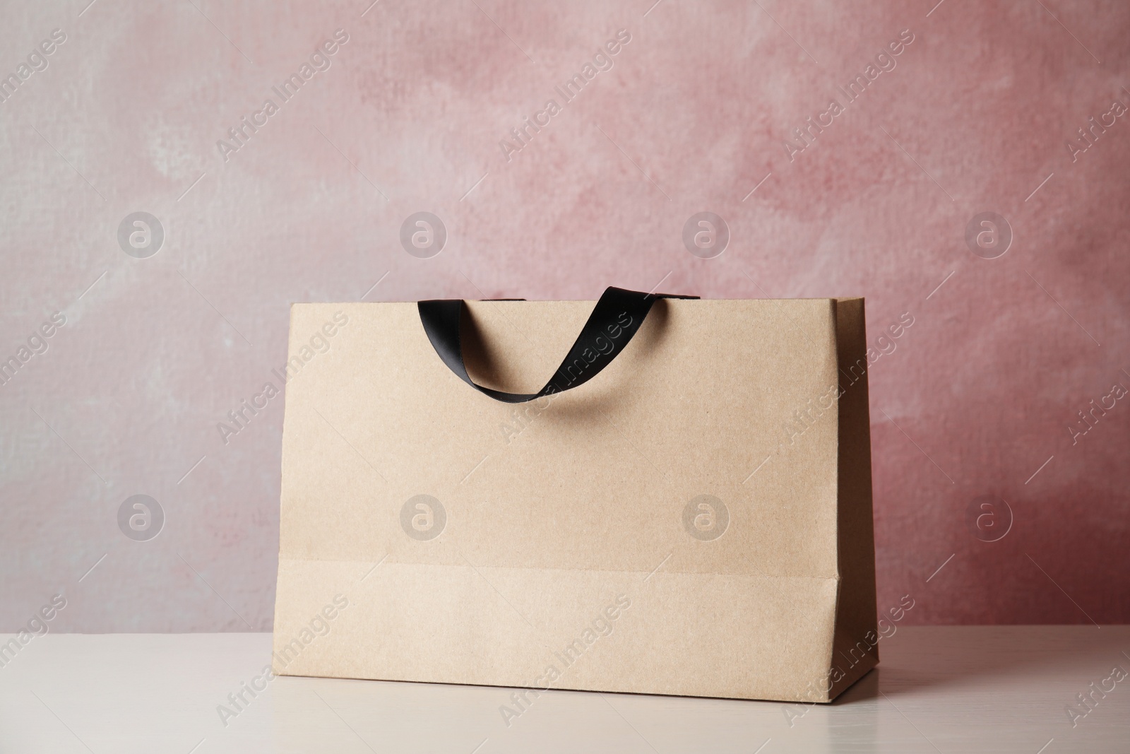 Photo of Paper shopping bag on table against color background. Mock up for design