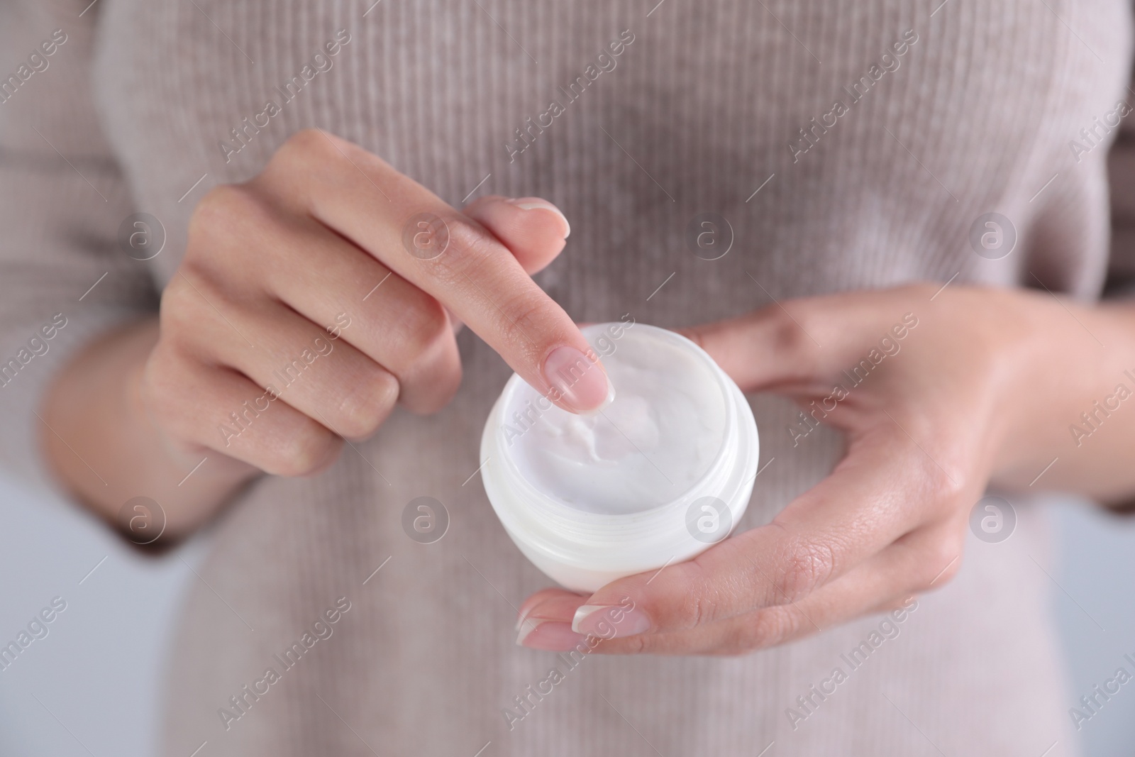 Photo of Young woman holding jar of cream, closeup