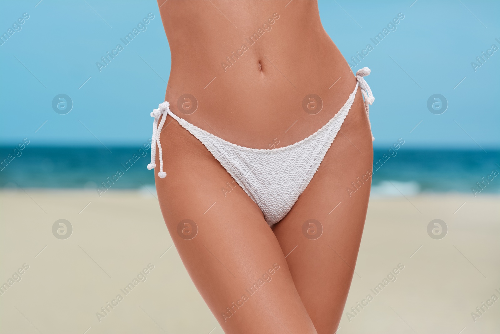 Image of Woman in stylish white bikini on sandy beach near sea, closeup