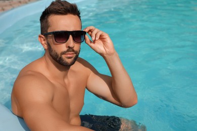 Photo of Handsome man resting in outdoor swimming pool on sunny summer day