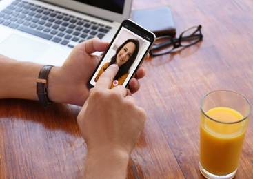 Image of Man visiting dating site via smartphone at table, closeup